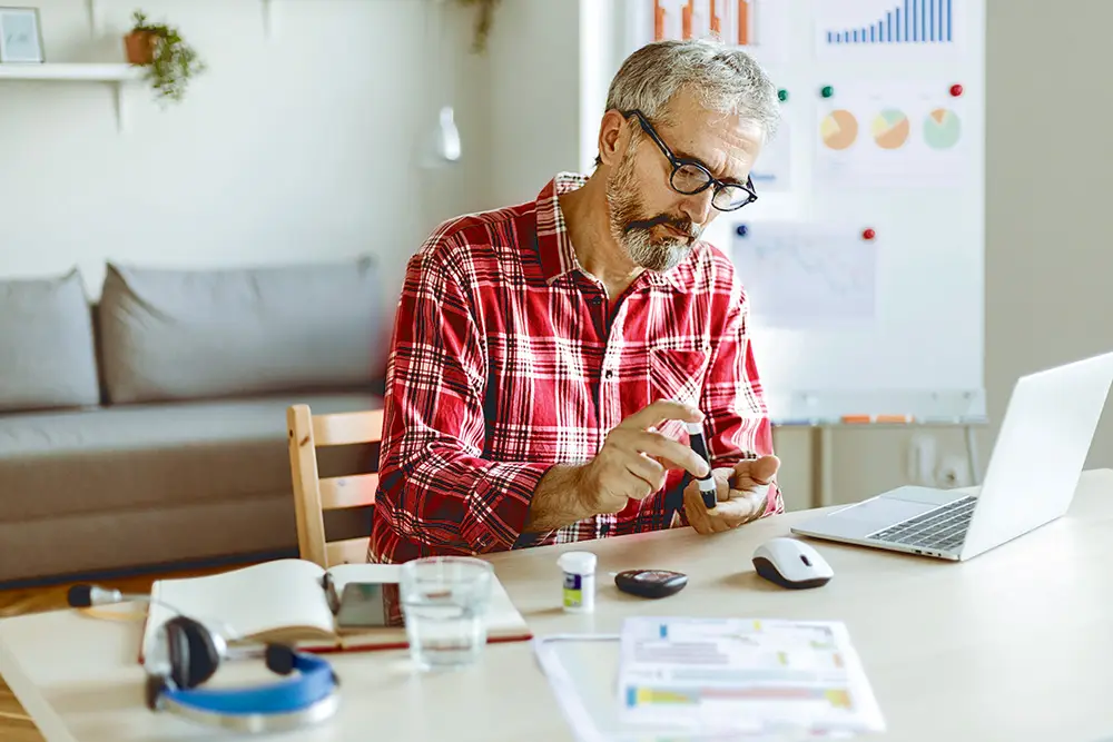 A senior man testing his blood sugar at home