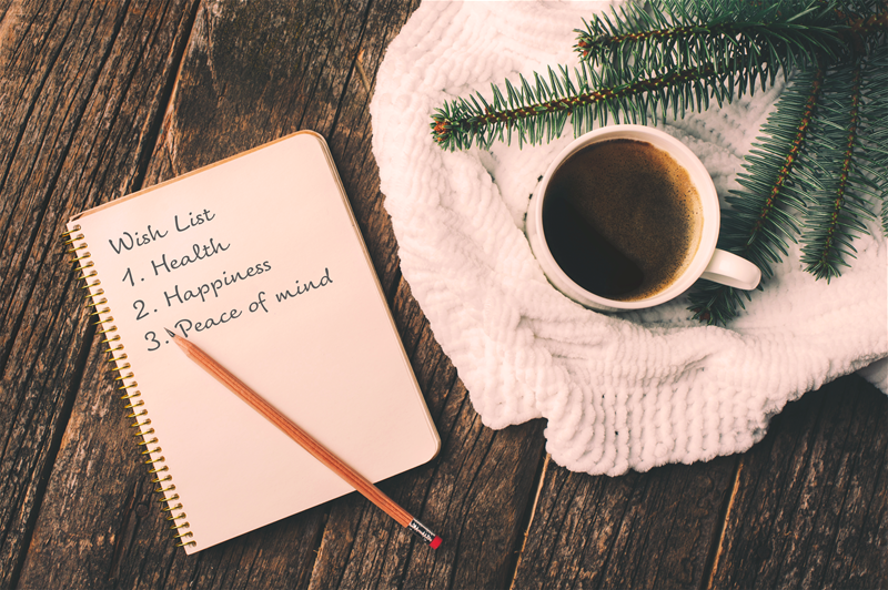 A notebook listing "Wish list 1. Health, 2. Happiness, 3. Peace of mind" sitting next to a cup of coffee