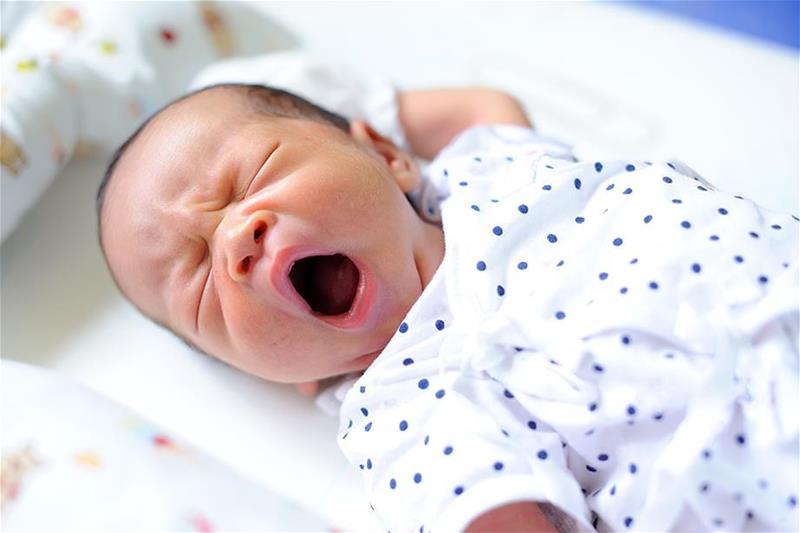 Infant with eyes closed and mouth wide open in a yawn