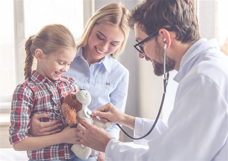 Doctor using a stethoscope on a child's stuffed animal during the child's visit to the doctor