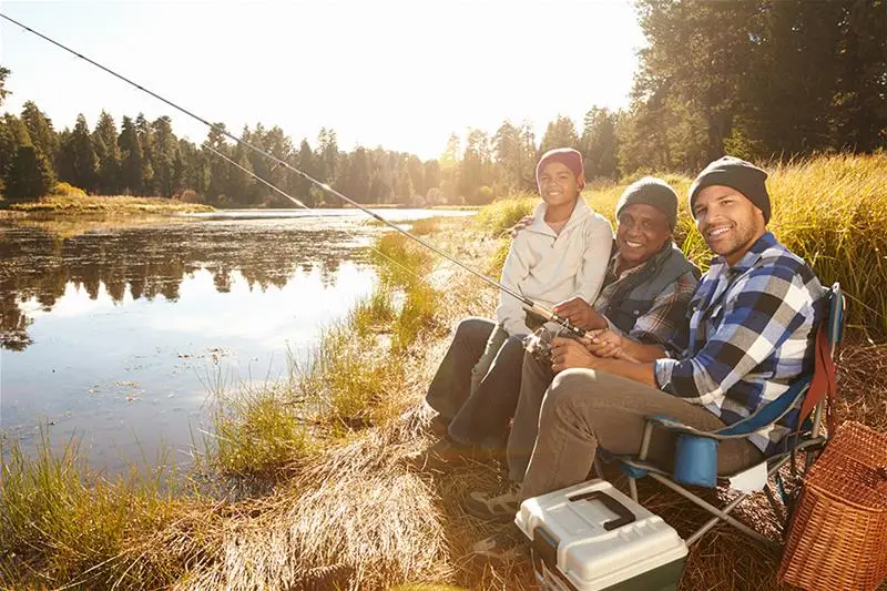 A senior, young man, and child fishing in a lake