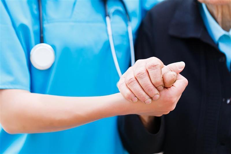 Nurse holds a patient's hand
