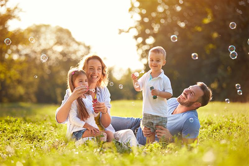 Family blows bubbles together in a field