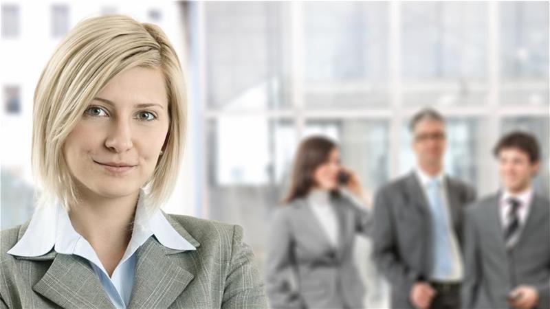 Professional woman looking at camera with co-workers in the background