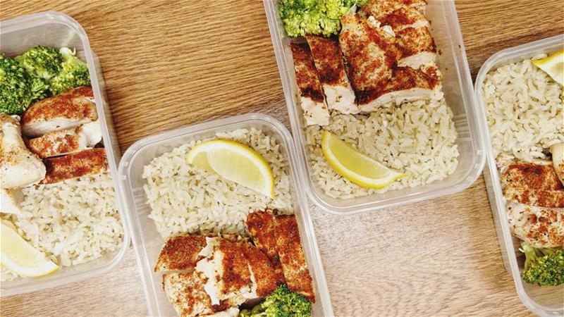 Four healthy-looking servings of chicken, rice, and cooked brocolli