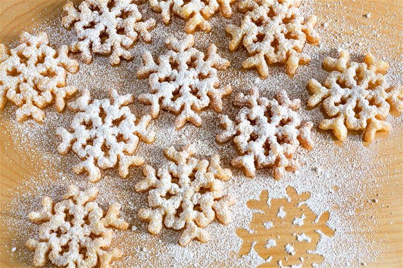 Snowflake-shaped rosette cookies dusted with powdered sugar