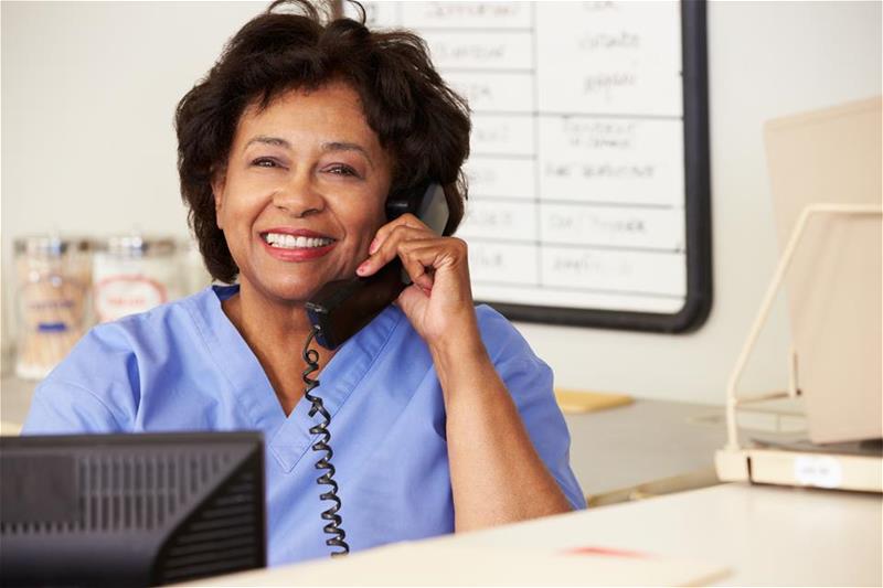 Nurse smiling while talking on the phone at a desk