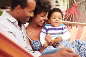 A couple swinging on a hammock with their infant son