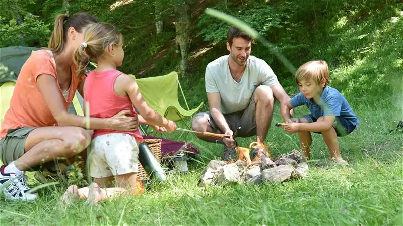 A family of 4 cooking over a campfire