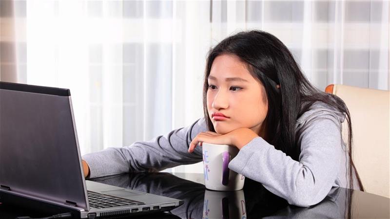 Young girl starting at computer screen looking glum