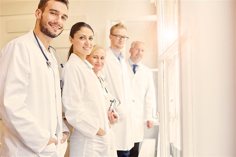 Diverse group of doctors in white coats standing in a line