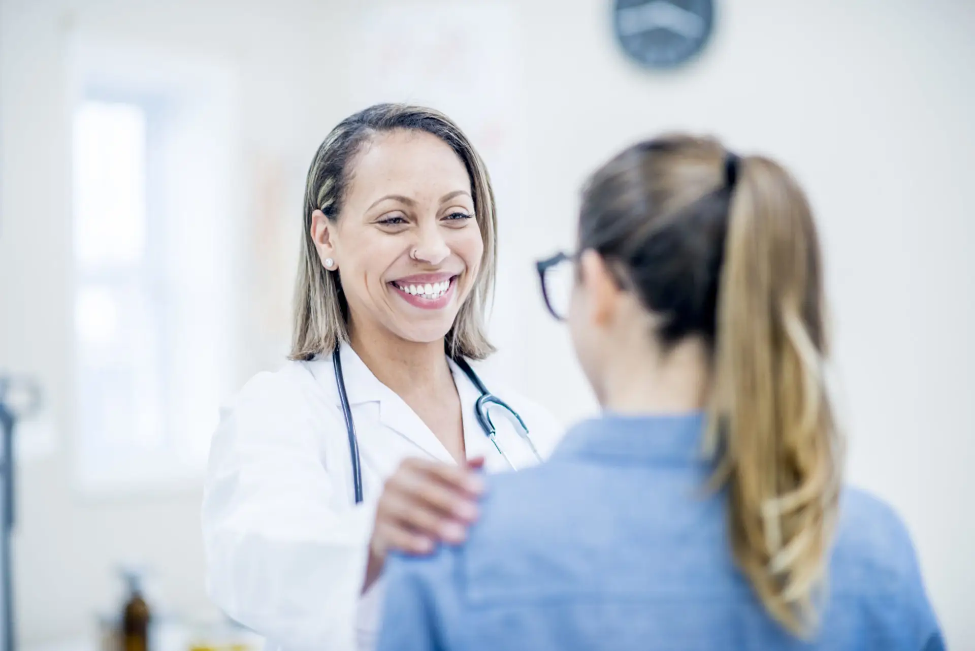 A healthcare professional smiling with her hand on a patient's shoulder