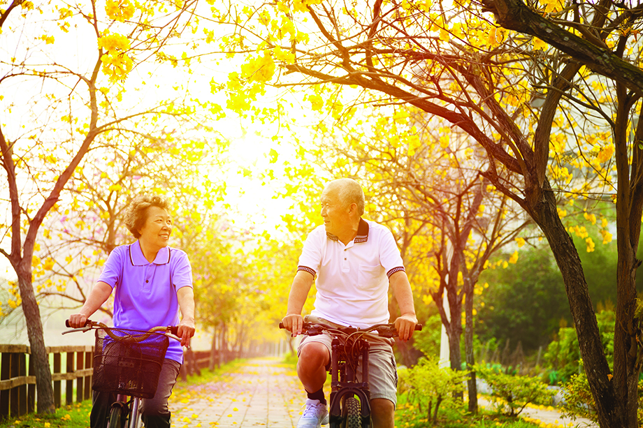 An older couple bike riding together in autumn