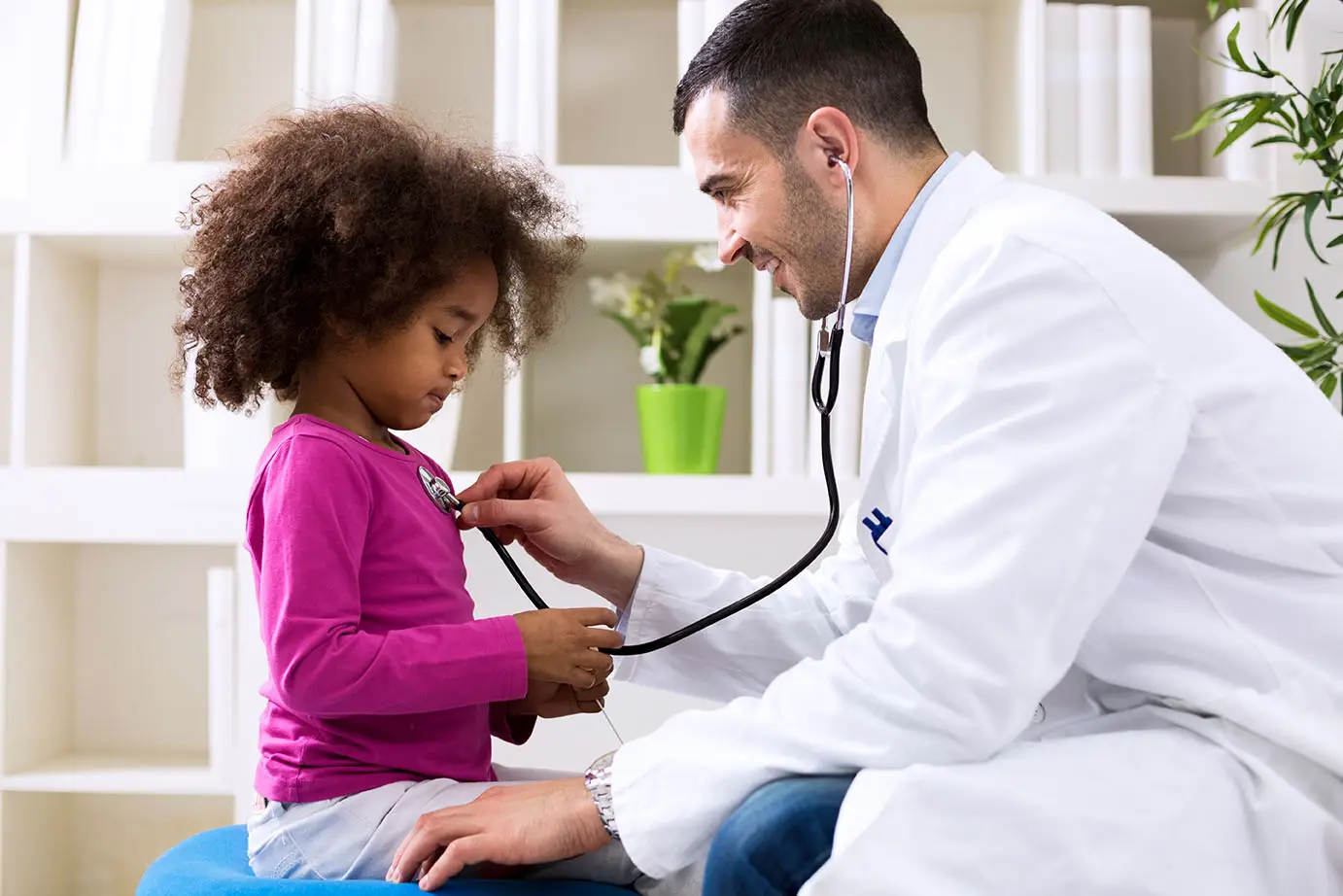 A doctor listens to a little girl's heart during a checkup