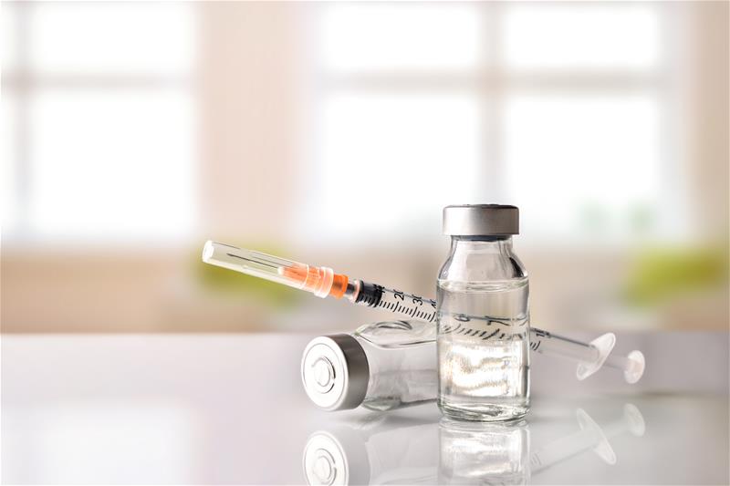 vaccine vial and needle sit on a counter