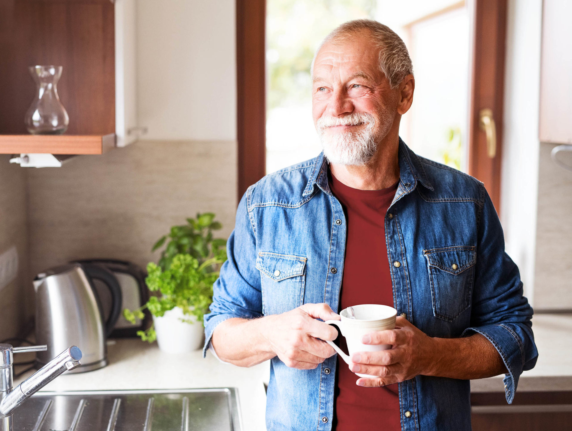 Hombre mayor disfrutando de un café en su cocina