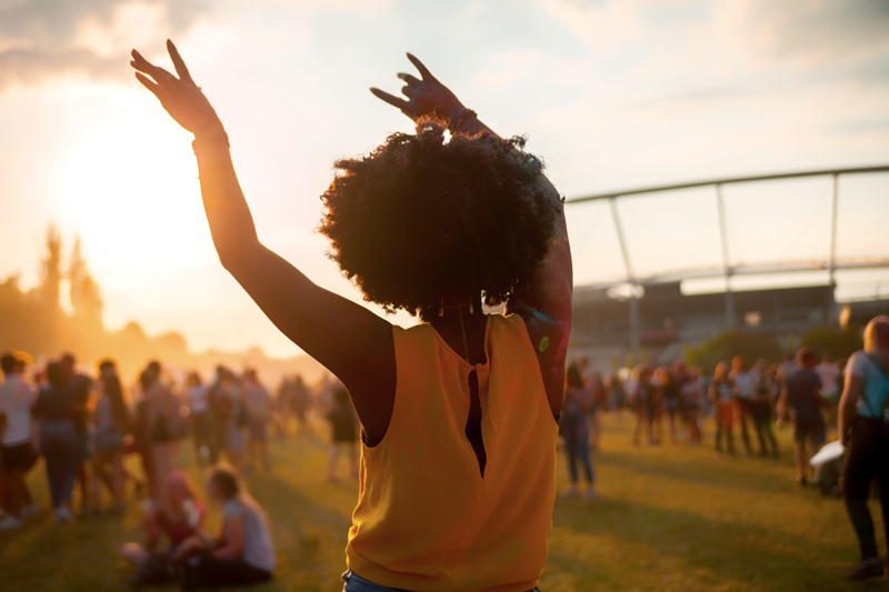 Joven con las manos en alto en un festival al aire libre