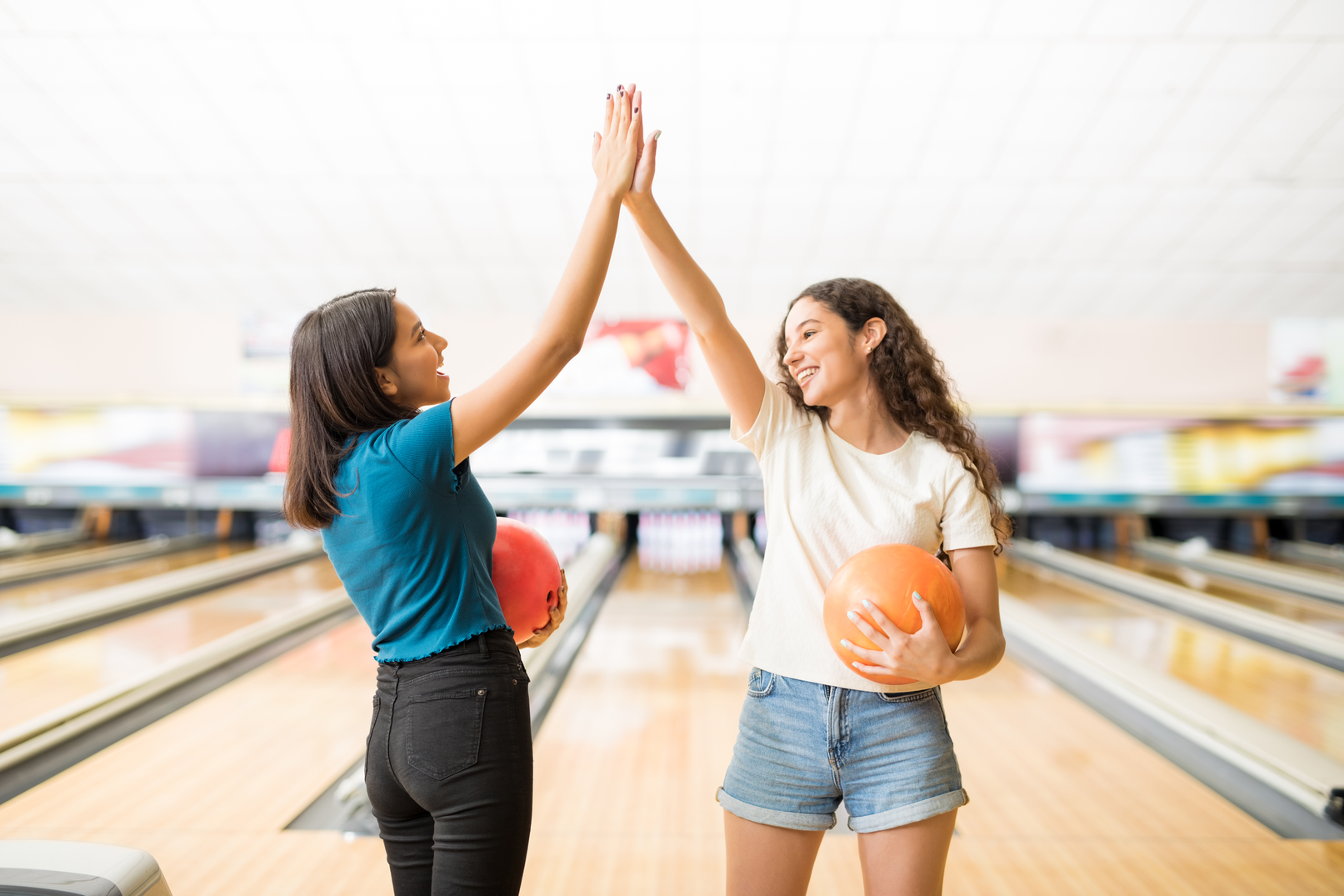 Two young woman giving a high-five while bowling