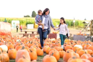 A mother and her 2 children at a pumpkin patch