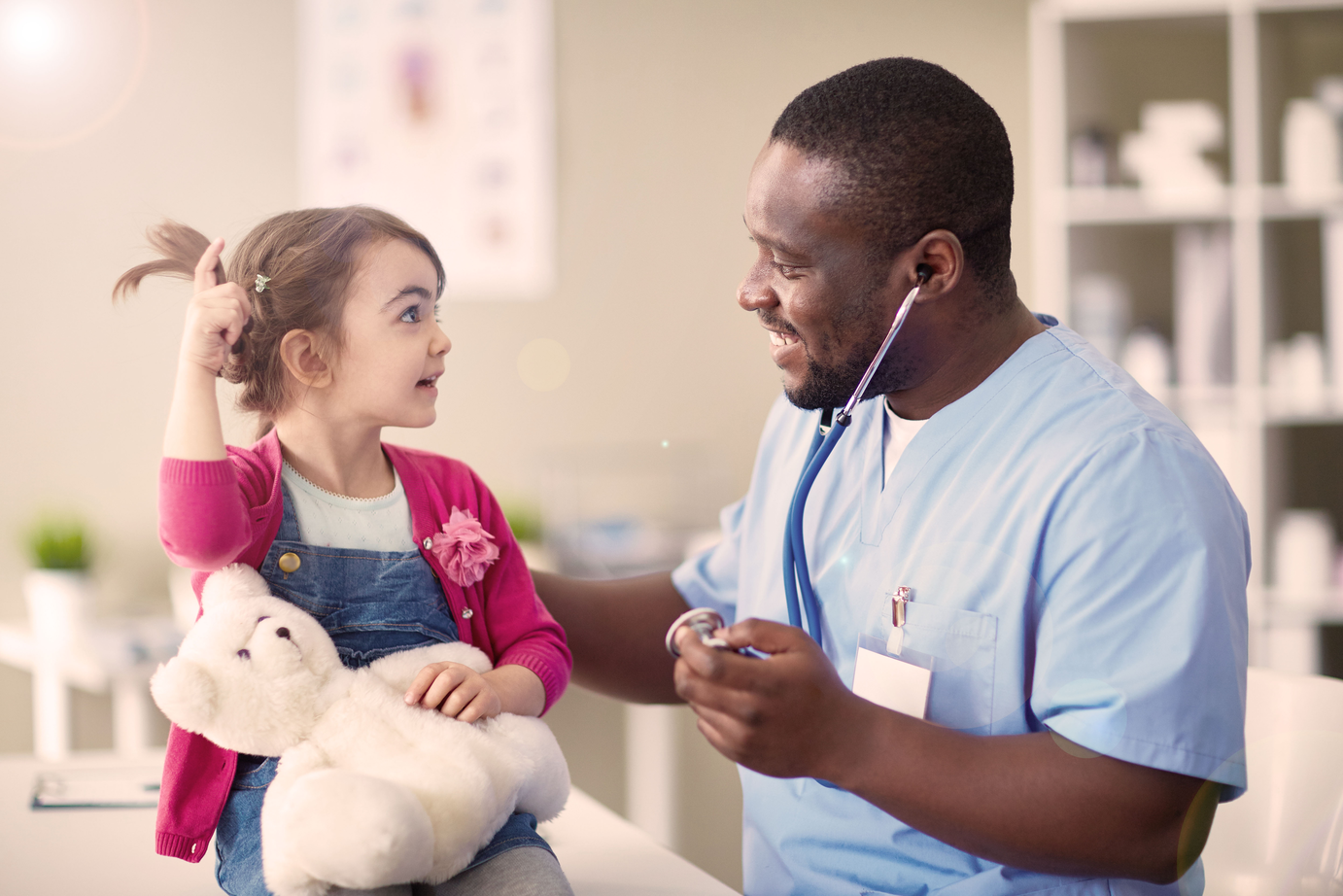 Little girl holding a teddy bear and telling her doctor a story