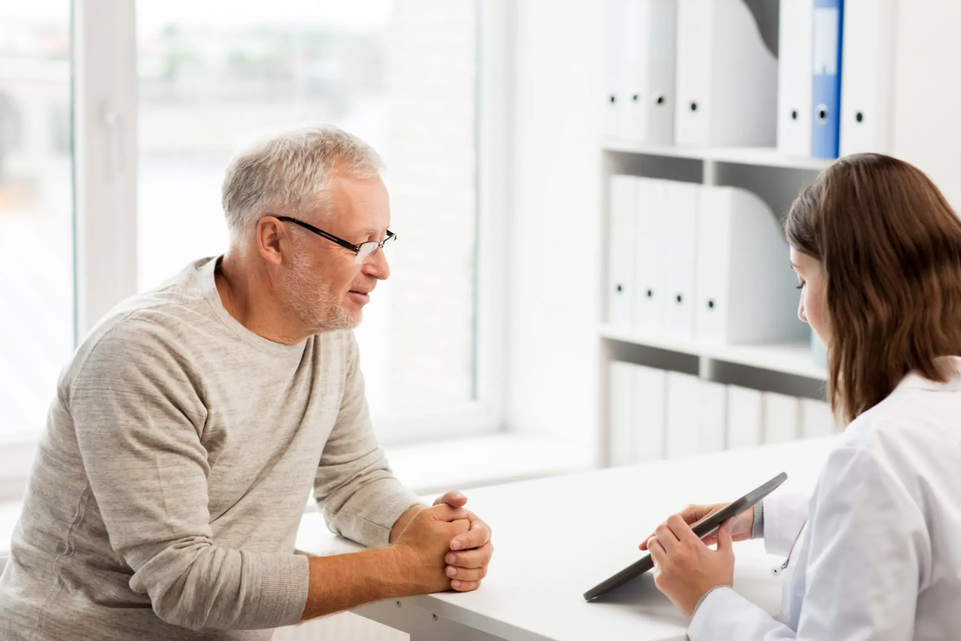 A doctor shows an older patient his medical result on a tablet