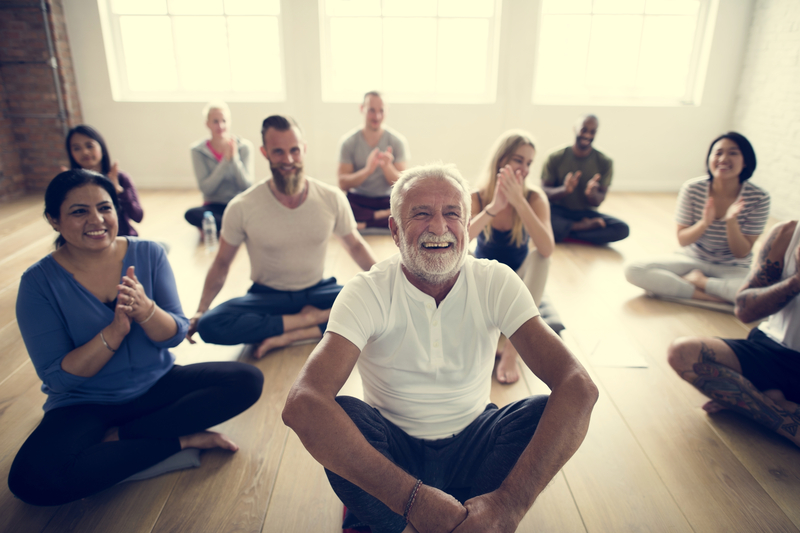 Senior sitting in middle of yoga class smiling