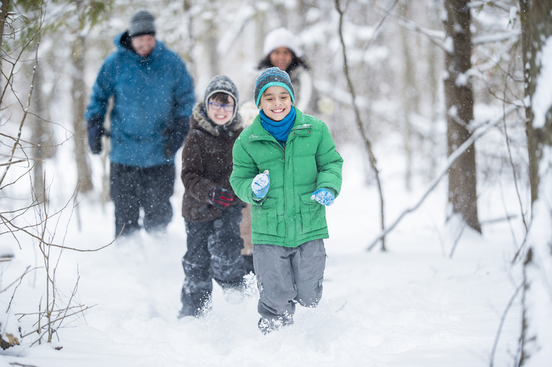 Family of four trekking through a snowy woods