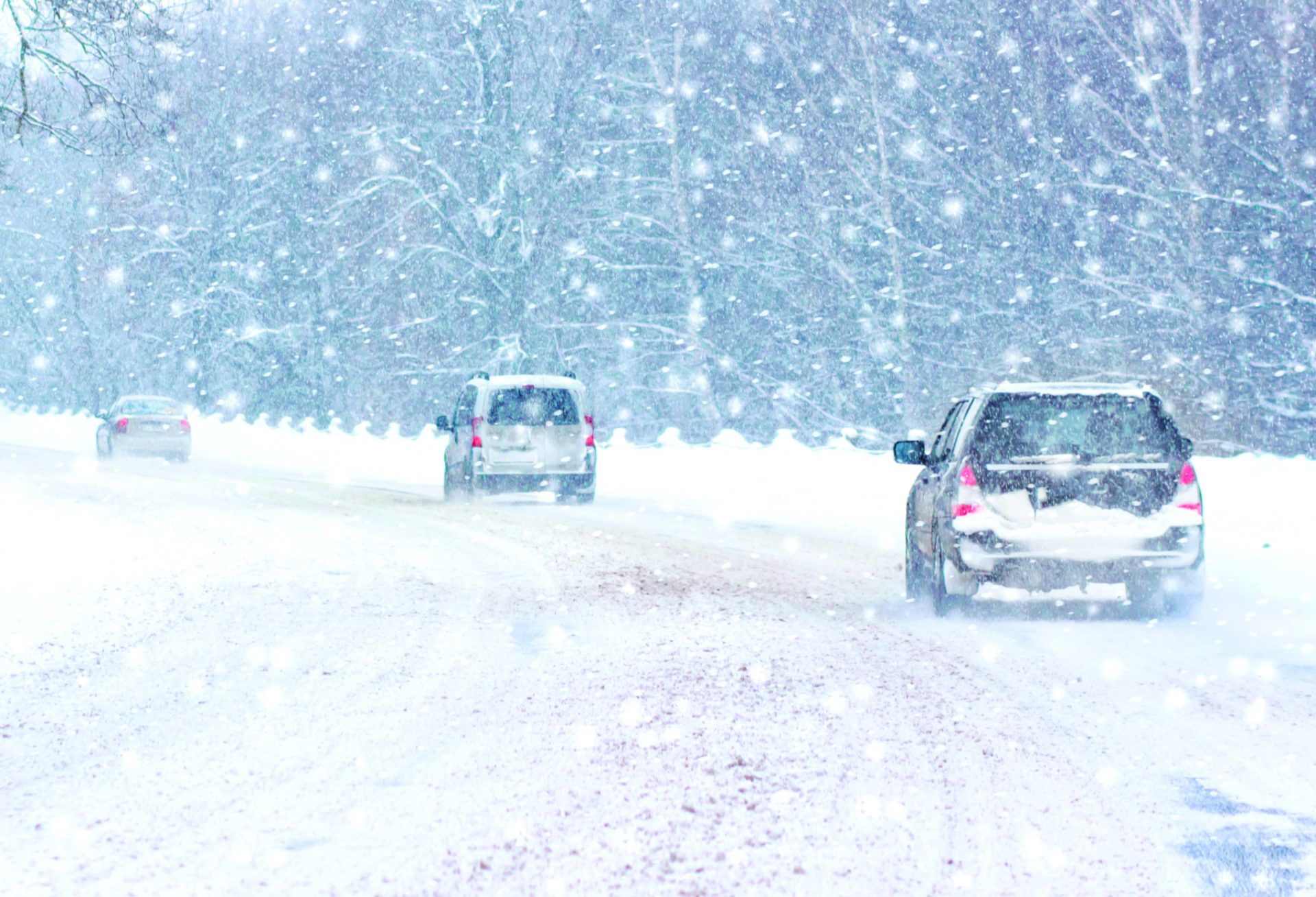 Cars drive on the road during a blizzard