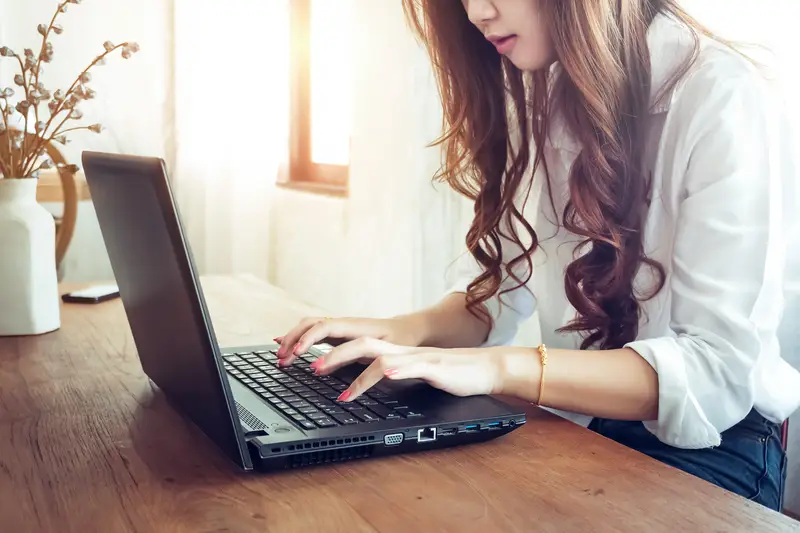A young woman typing on a laptop