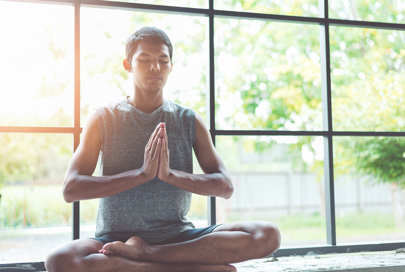 Young man meditating in front of window