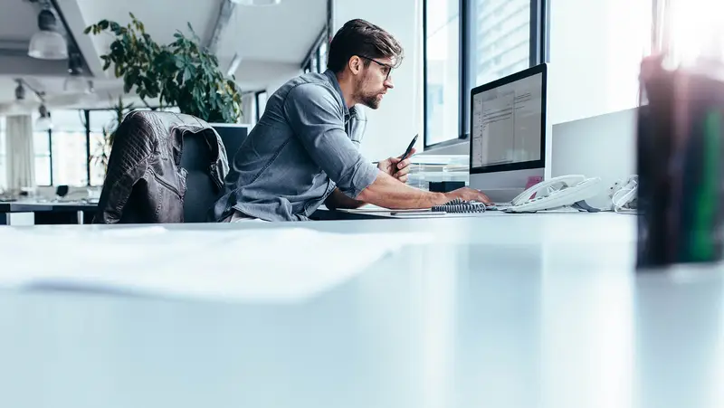 Un hombre en su escritorio trabajando con un ordenador