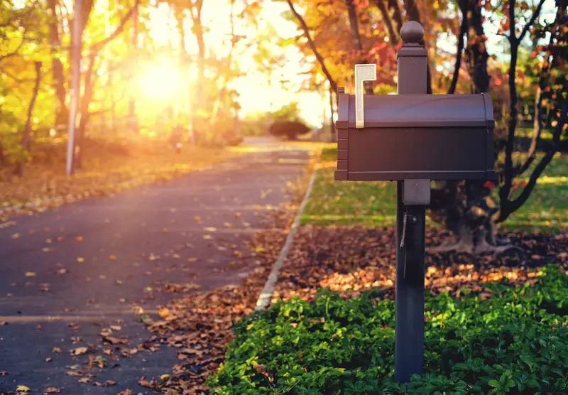 A mailbox with the flag up in a beautiful autumn neighborhood