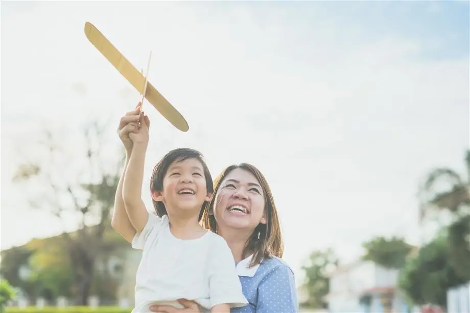 A woman holding a boy and a wooden airplane