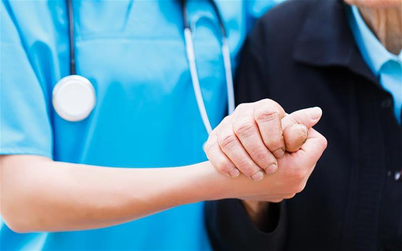 Health care provider holding senior man's hand