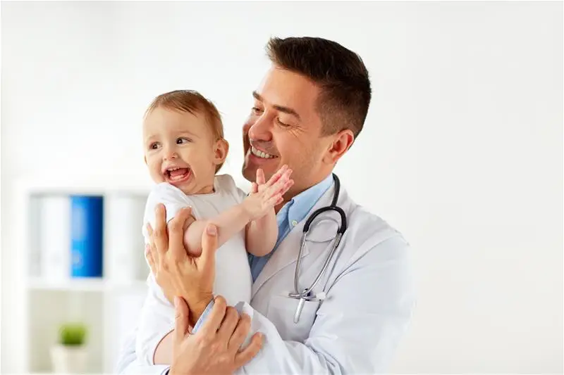 A doctor holding a young toddler