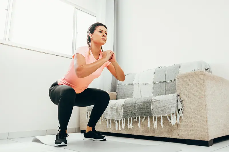 A woman doing squats in her apartment