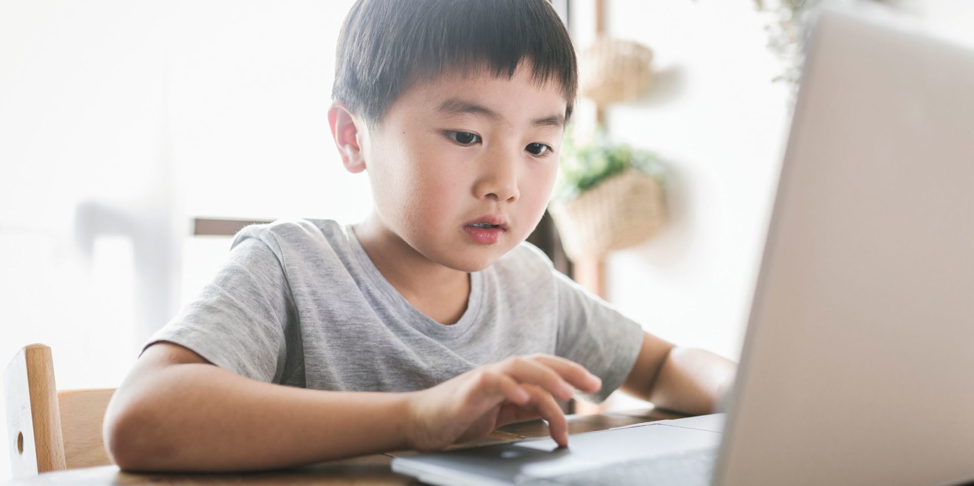 Little boy pressing a key on a laptop computer in front of him
