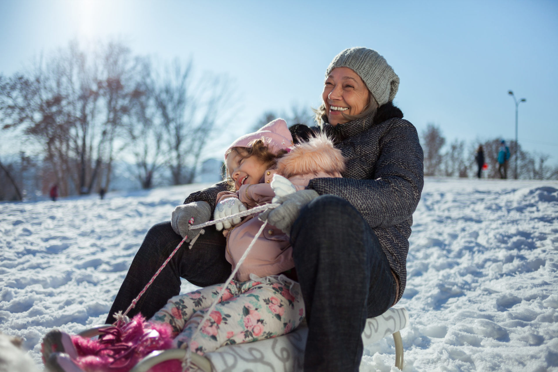 Woman sleds down a hill with her granddaughter