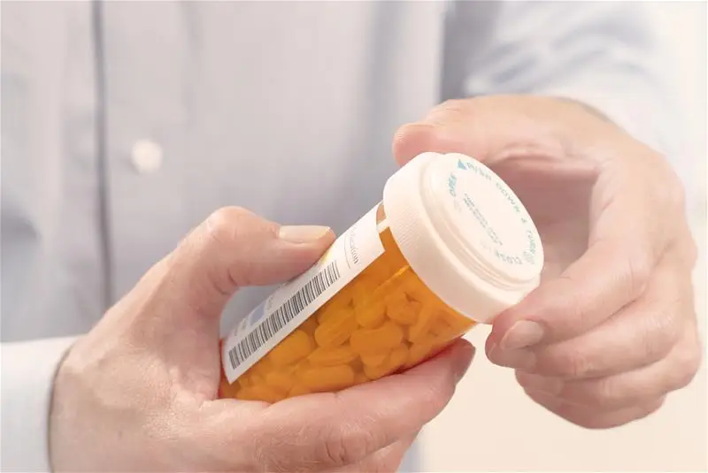 A man's hands holding a prescription drug container