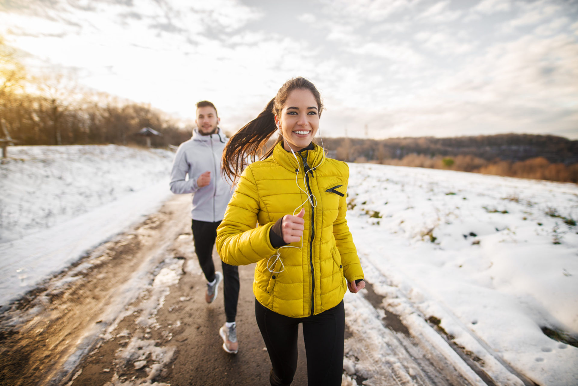 Young woman jogging in winter with young man following behind her
