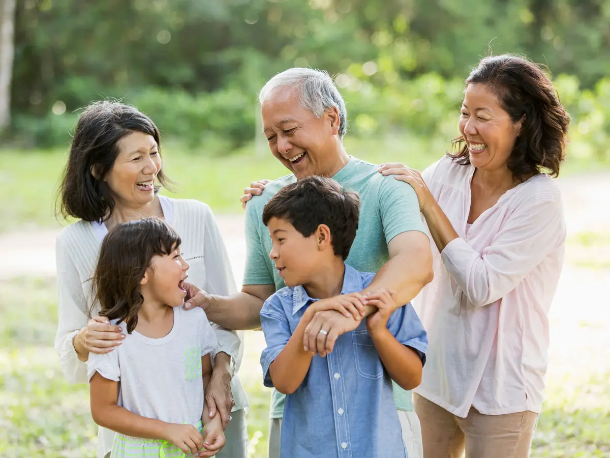 An Asian-American family smiling and laughing outside