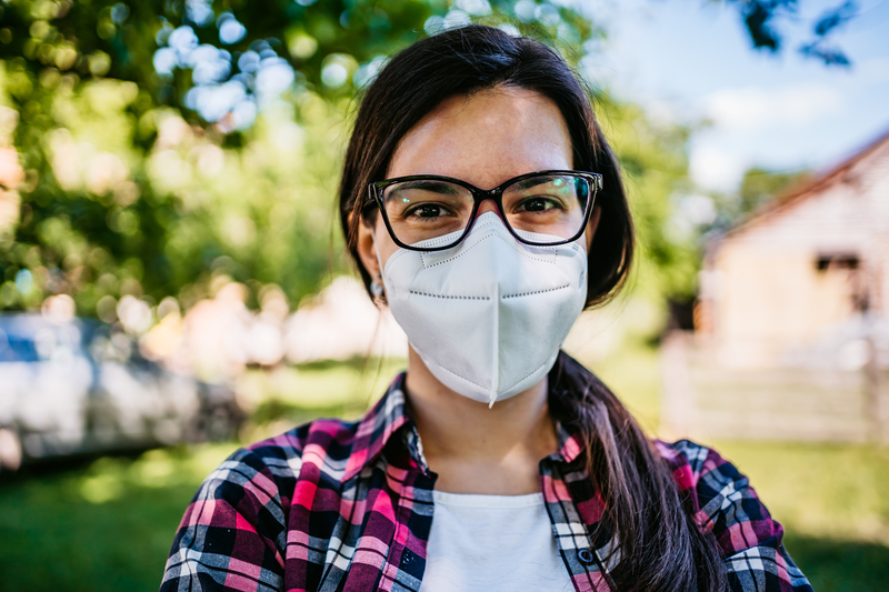 Young woman wearing a N-95 protective face mask while outdoors