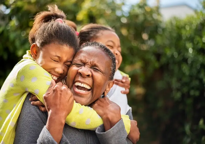 Two young girls embracing an older woman