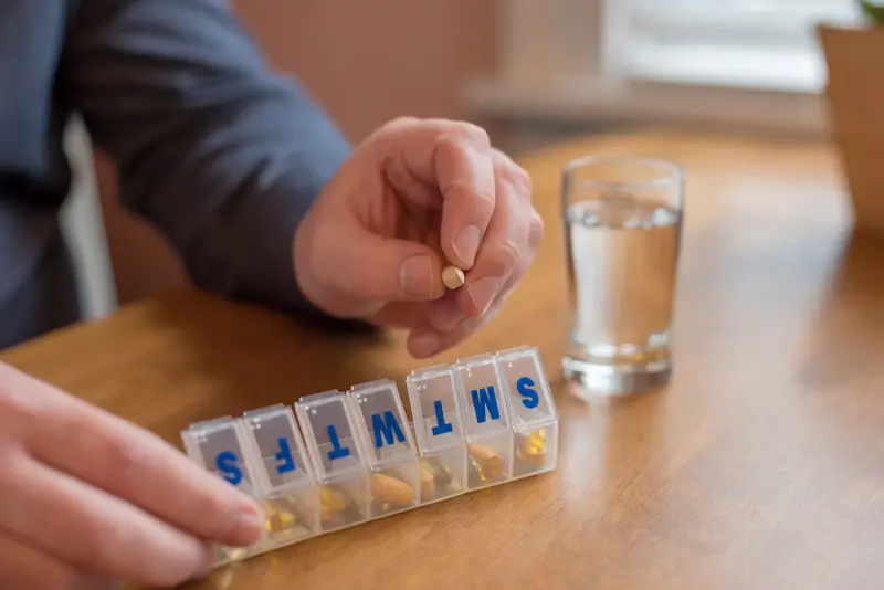 An individual placing pills in a pill case