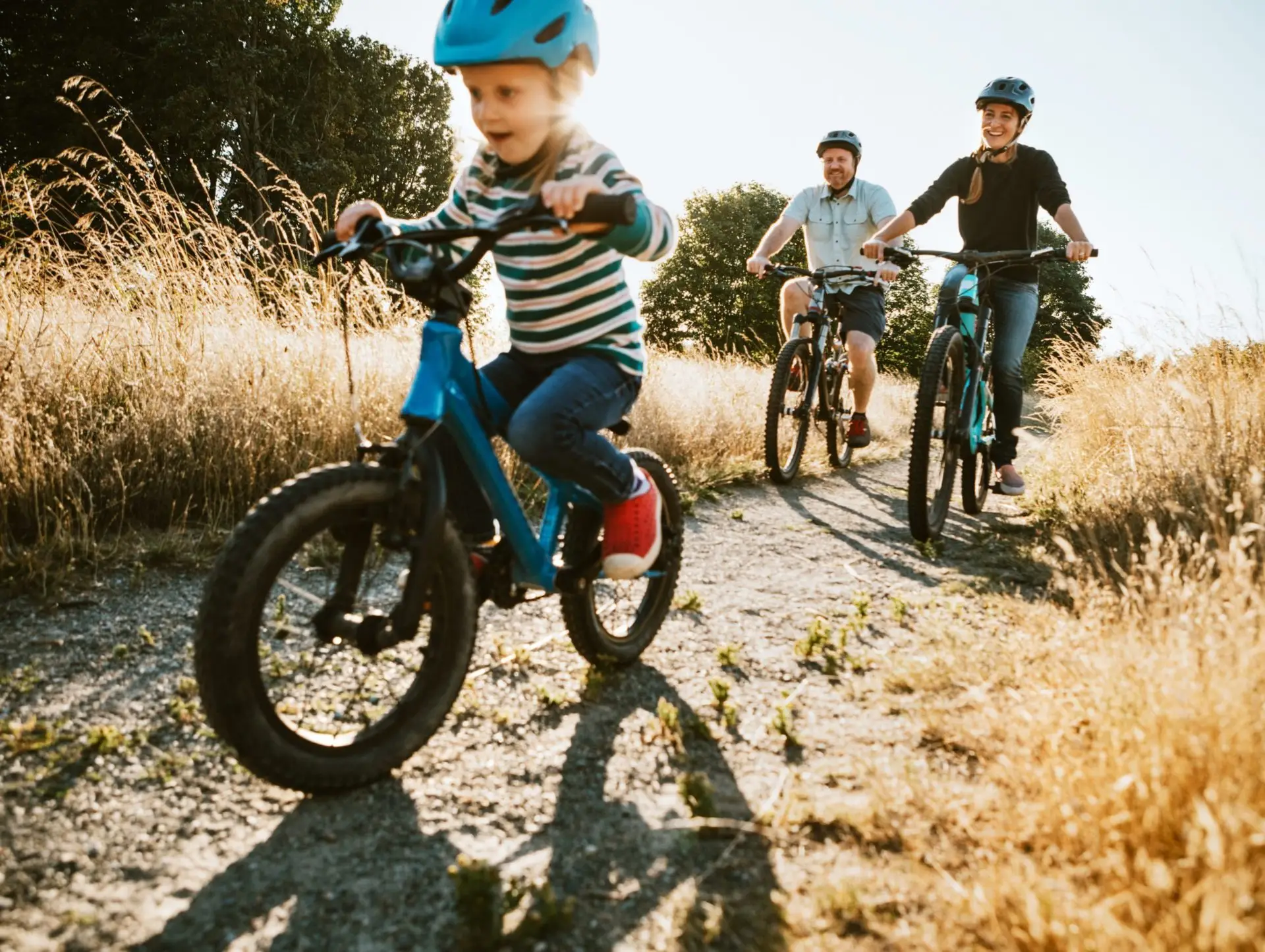 A family of 3 going for a bike ride on a trail