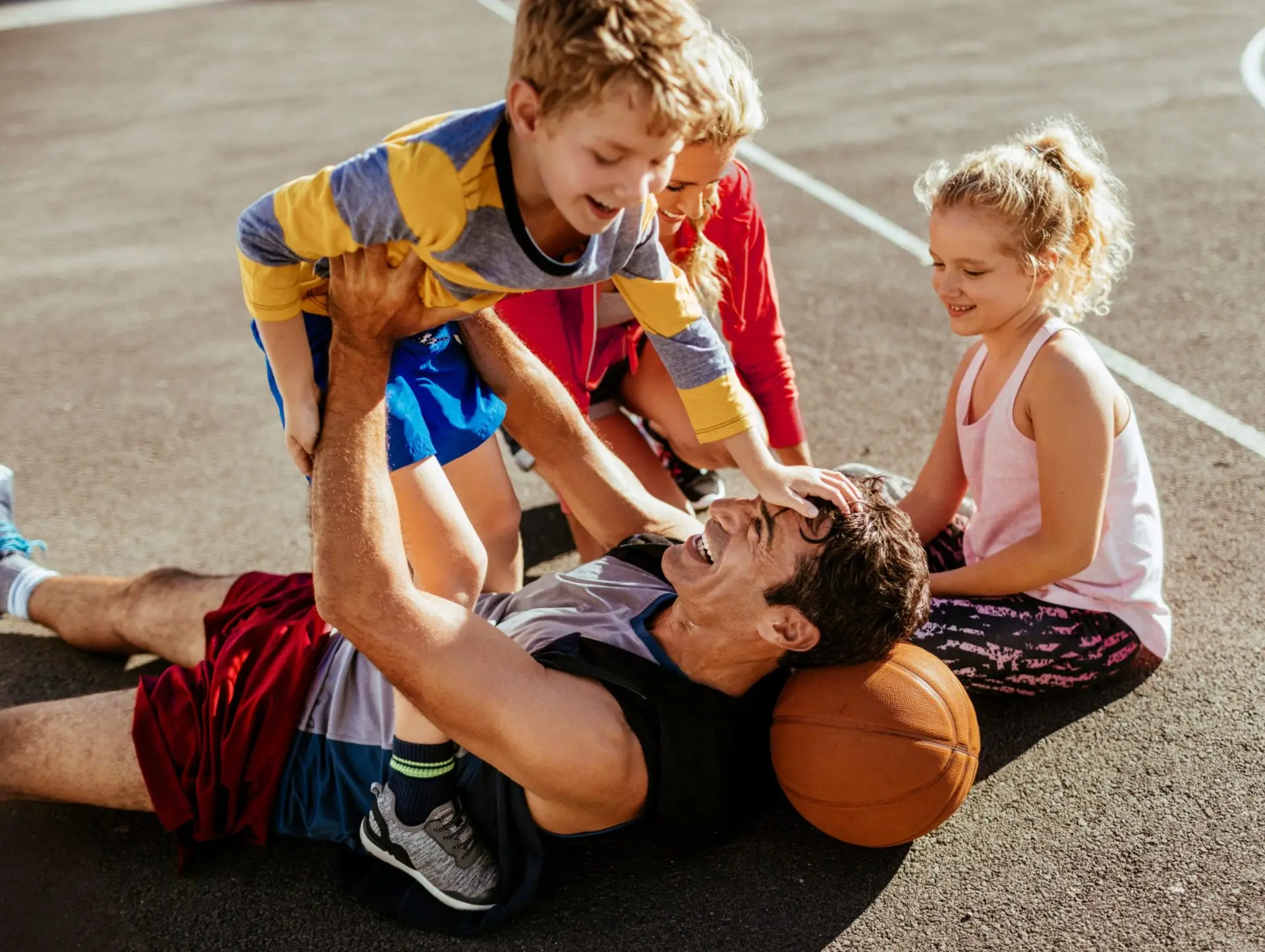 Una familia de 4 miembros jugando juntos al baloncesto