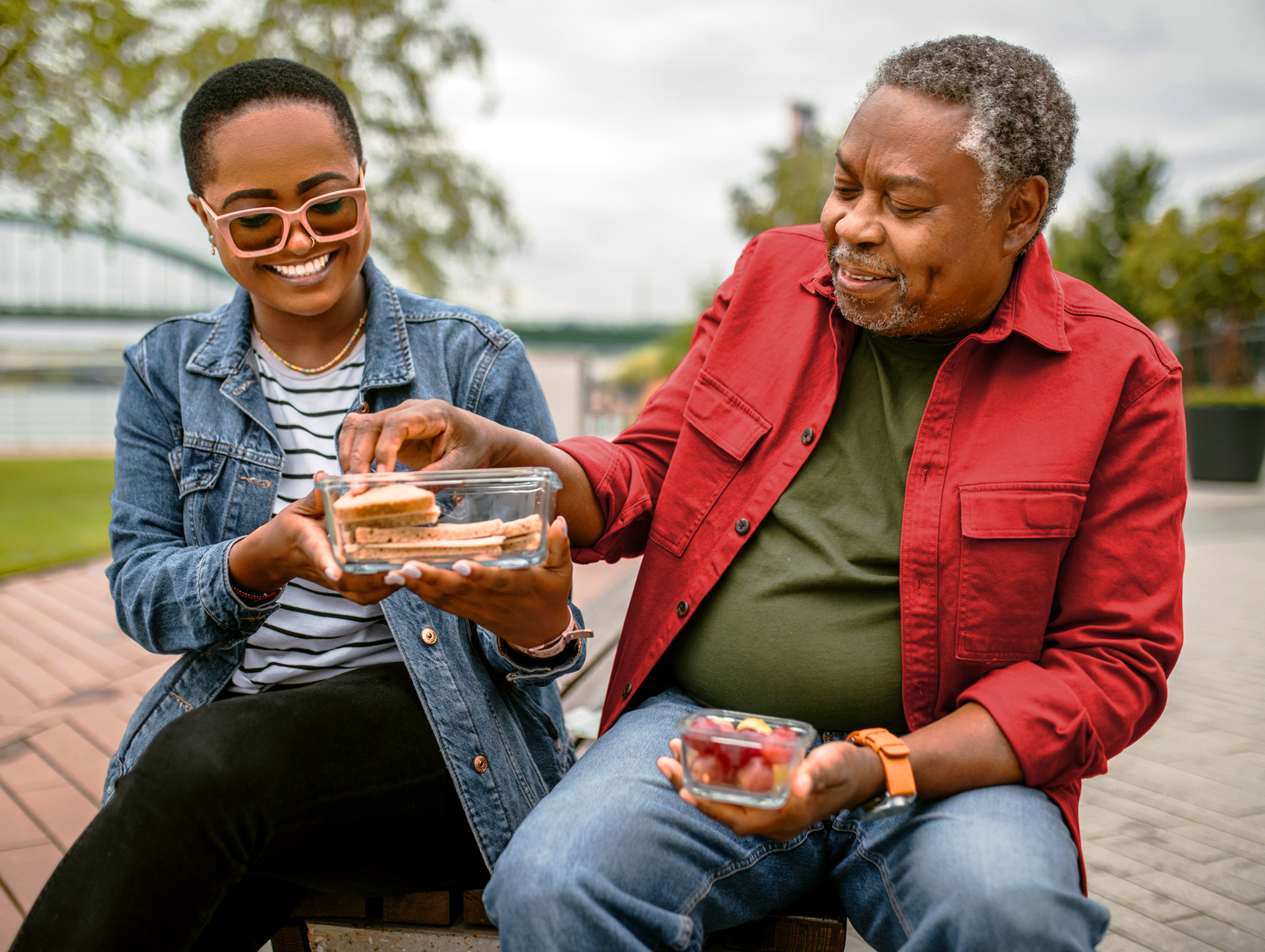 Senior couple sitting on a park bench together and sharing food