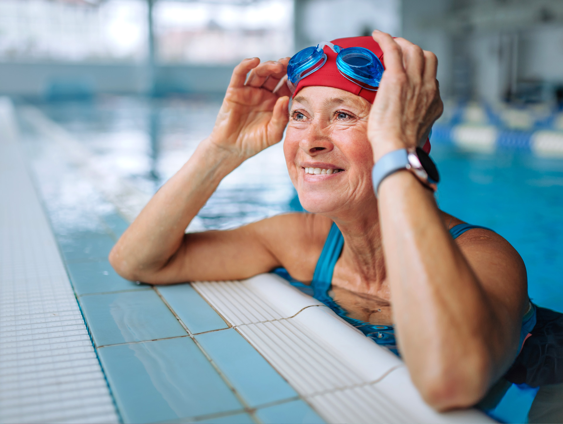 Senior woman smiling at the edge of an indoor pool