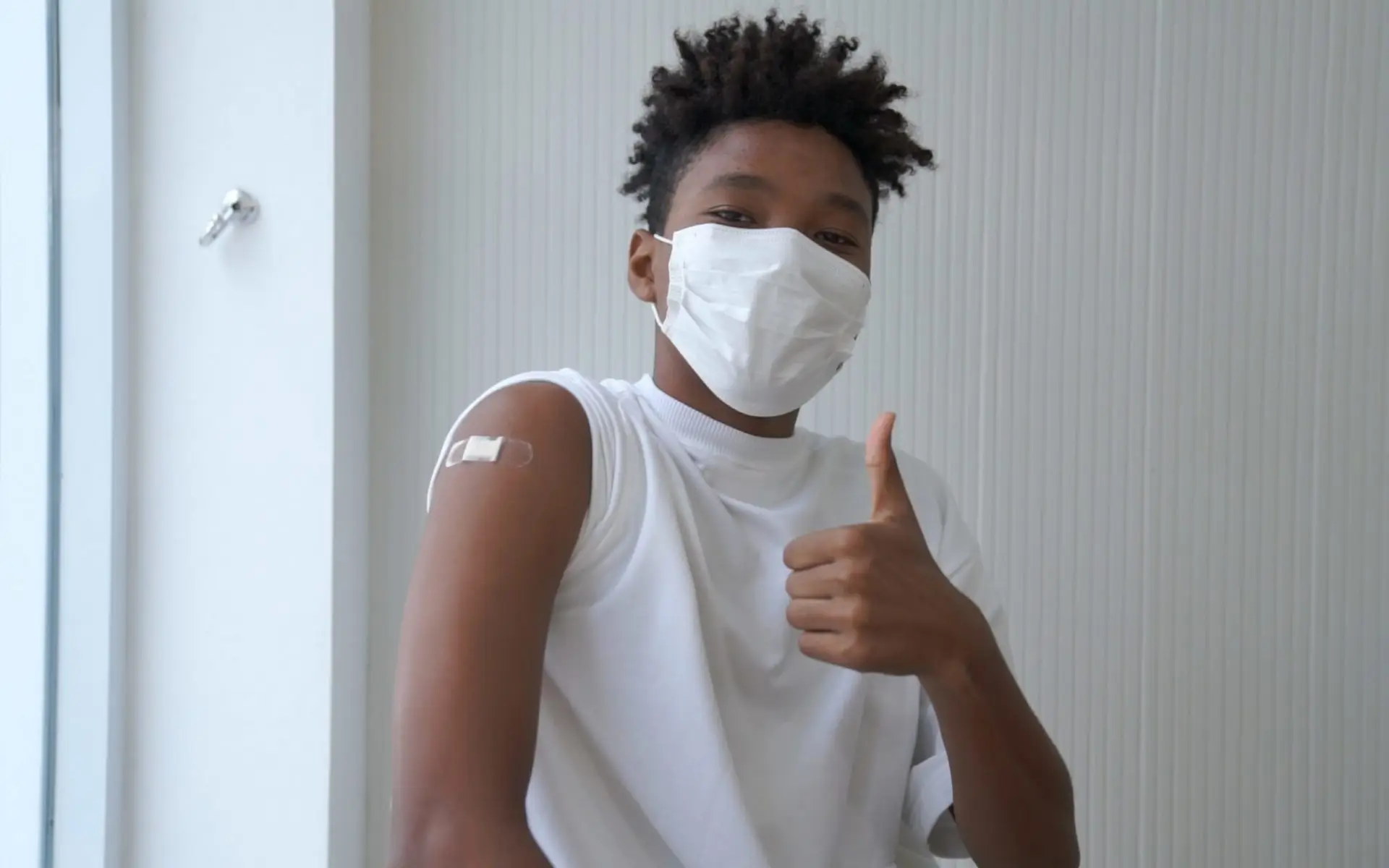 A boy wearing a face mask who approves getting vaccinated