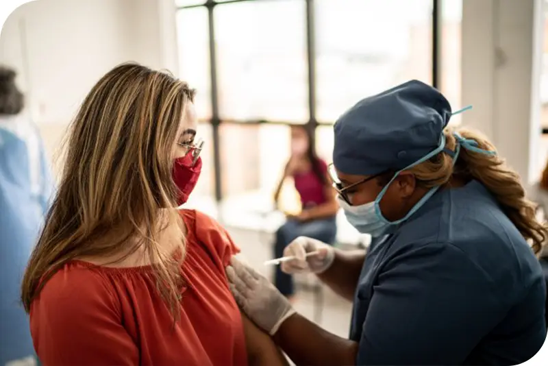 A woman getting vaccinated by a healthcare professional at a clinic